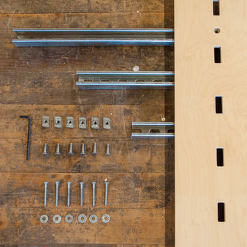 Top view of hardware neatly organized on a wooden floor. Unistrut, allen key, square nuts, panel screws, lagbolts, and washers.