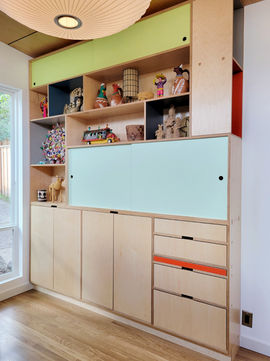Modern built-in cabinet with open shelves, sliding doors, and colorful accents, displaying decorative items and collectibles.