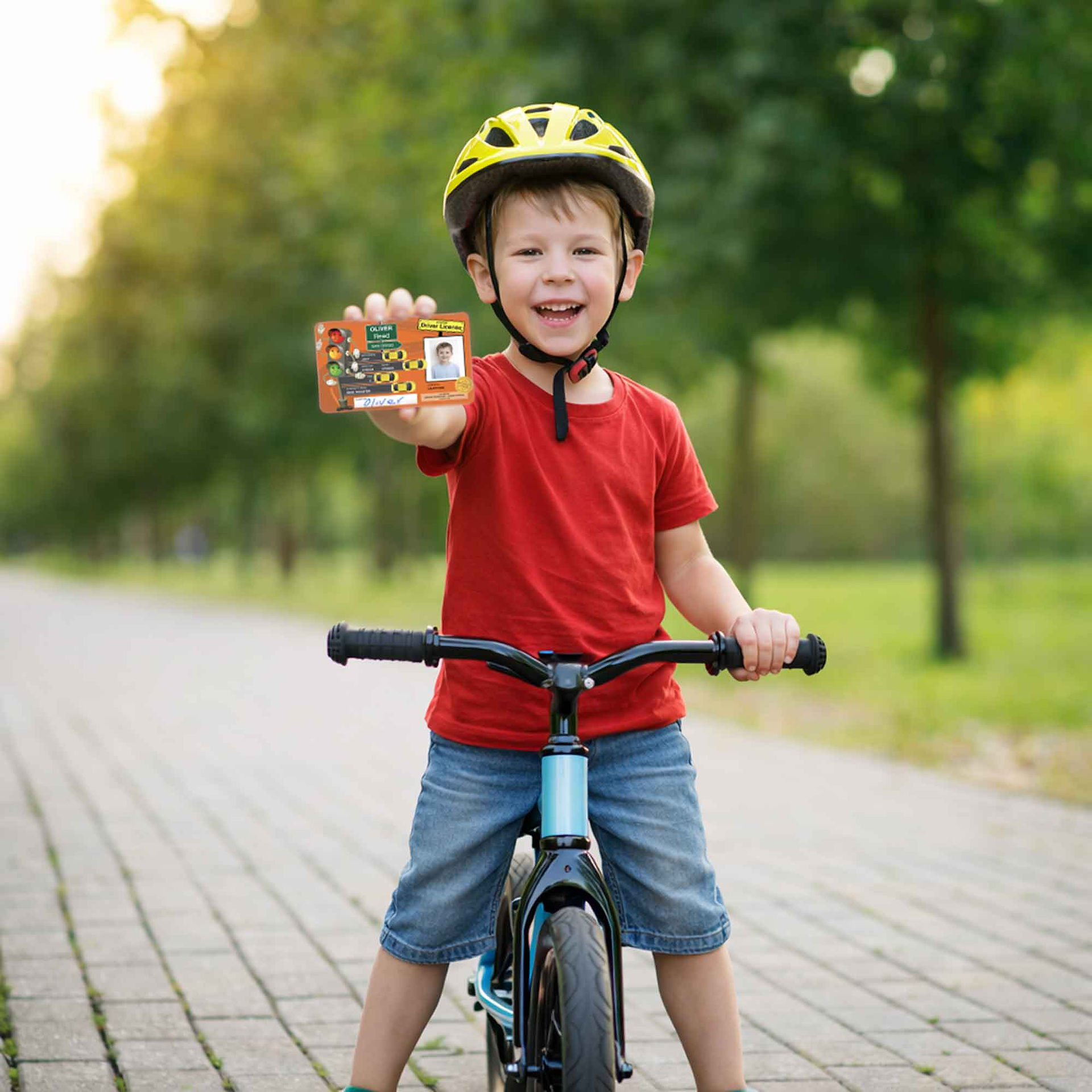 Child proudly showing his junior driver licence while wearing a helmet and straddling a bike