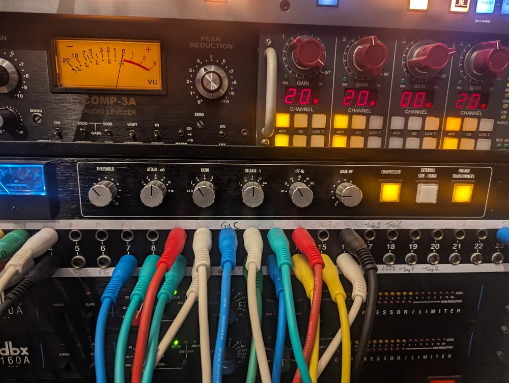 Détail du matériel de prise de son et de mixage du studio, avec les vumètres et le patch de câbles