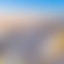 A wide sunset view of the whitewashed buildings and blue-domed churches of Oia, Santorini, overlooking the Aegean Sea.
