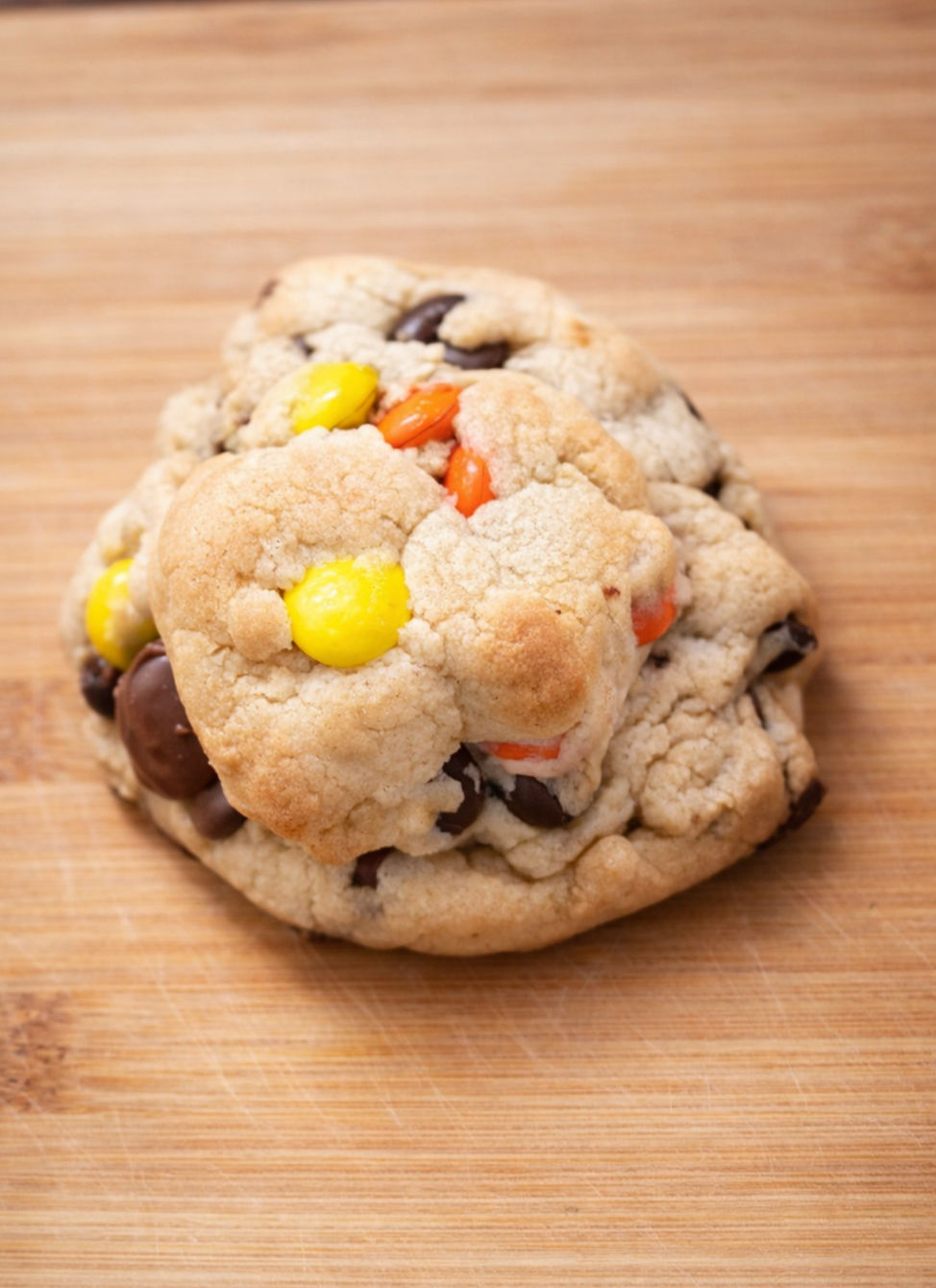 Delicious chocolate chip cookie with colorful candies on wooden surface.