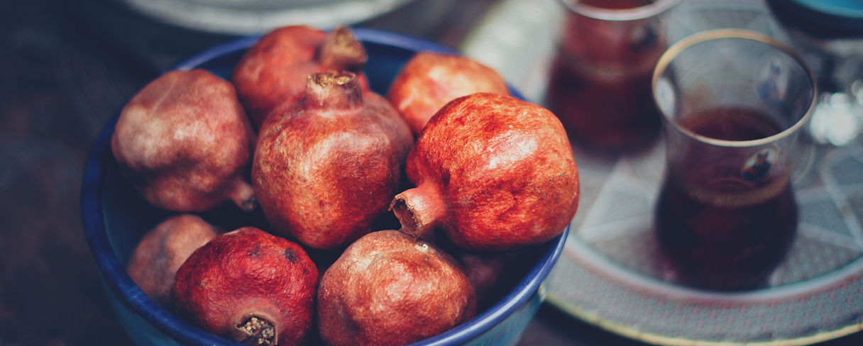 Granatapfel in blauer Schale mit Teegläsern