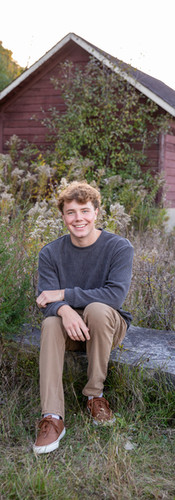 boy sitting on rock in field 
