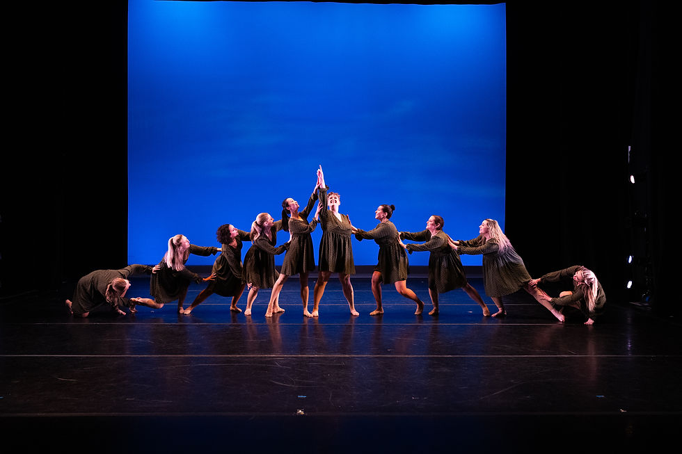Adult dancers in a group synchronized pose on stage