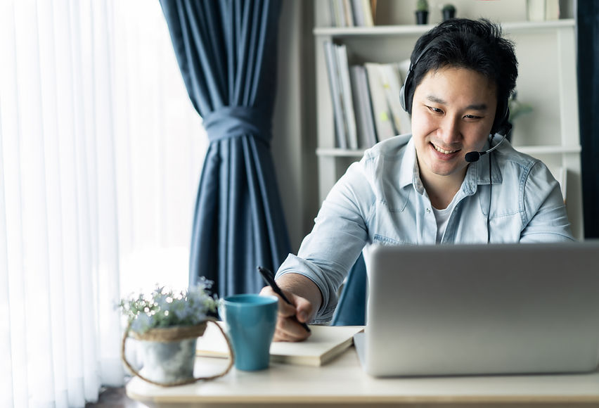 Asian businessman talking to colleague team in video call conference writing note on book