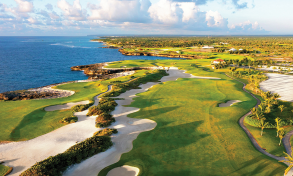 Expansive view of Corales Golf Course with lush fairways and turquoise Caribbean Sea in the background