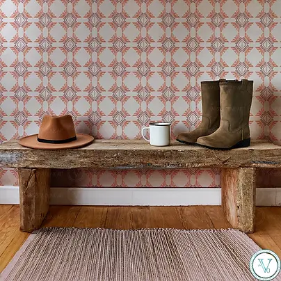 Wallpaper featuring a repeating Southwestern motif in terracotta on a blush background from the Desert Storm collection, styled with a rustic bench, hat, mug, and boots by Vanessa Olink Art