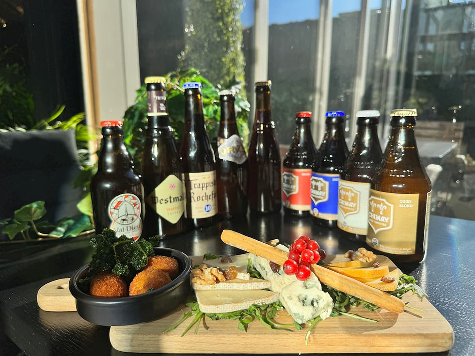 Planche gourmande avec assortiment de fromages, croquettes et bières trappistes disposés sur une planche en bois 
 
