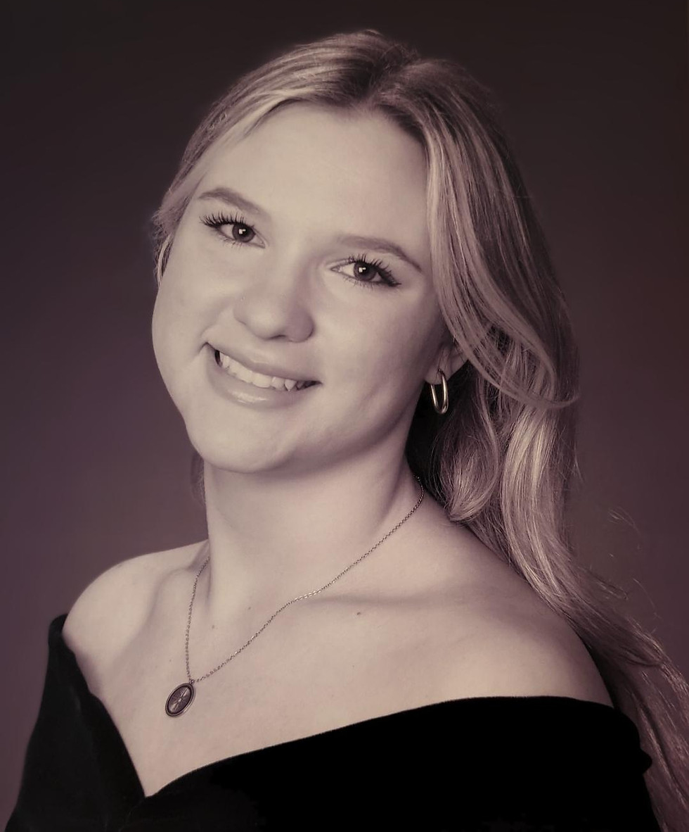 A monochromatic picture of author Adrianna Pakes. She is smiling, is wearing a necklace, and a black v-neck top.