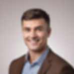 clean background. man with slight smile. short brown hair.jpg