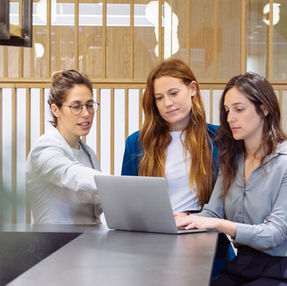 Team of designers choose accessible images, looking at laptop screen together, one woman points to screen
