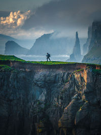 Photographer facing dramatic sea cliffs during a Faroe Islands photo tour.