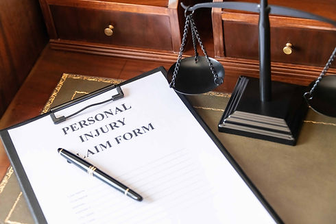 Personal injury claim form on a desk with scales of justice and a pen, representing accide