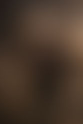 PAYDAY 3 heister in a white clown mask and orange goggles shushing the camera while holding a customised rifle inside a vault stacked with cash.