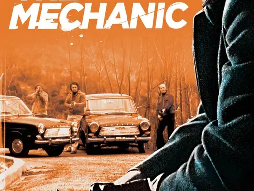 Film poster for The Mechanic (1972) showing Charles Bronson crouched with a pistol in hand, staring coldly ahead, while armed men stand near vintage cars on a deserted road under an orange-tinted sky, conveying a tense, ruthless crime atmosphere.