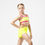Thumbnail: Girl in neon yellow two-piece with pink-trim crop top and matching wrap skirt over briefs, hand on hip, white background.