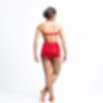 Back view of dancer in red halter top and fringe skirt on white background.
