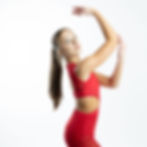Red cutout leotard with open side, dancer posing with raised arms.