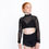 Thumbnail: Dancer in black mesh long-sleeve crop over bra top and black shorts, looking up.