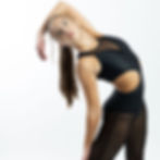 Black mesh-panel unitard with side cutout, dancer bending in studio.