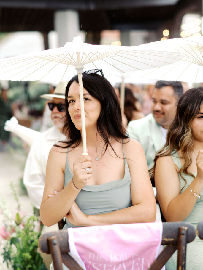 A guest at a wedding reception holds a parasol to shield herself from the rain during a wedding ceremony in Austin.