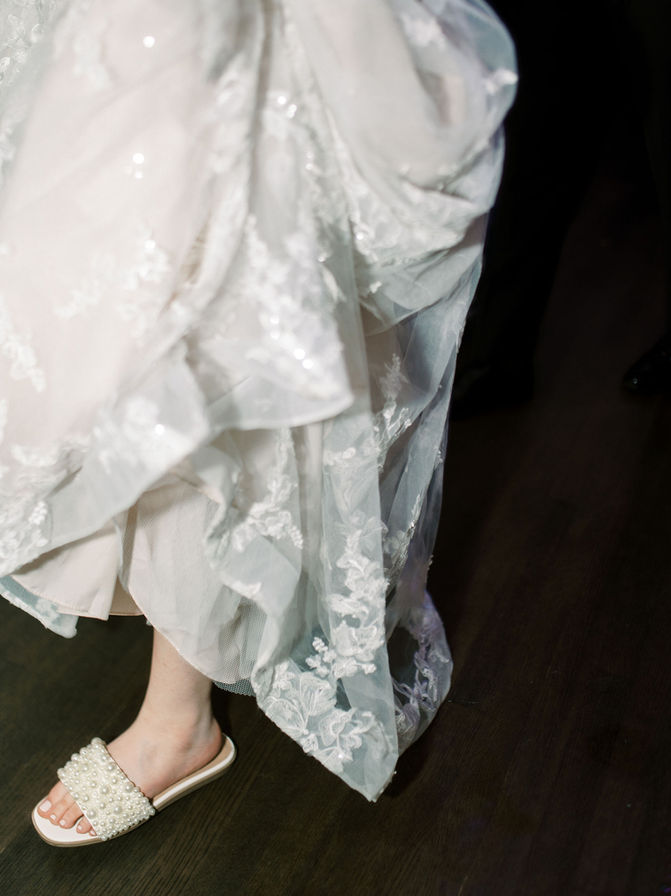 Bride’s lace wedding dress and shoes detail.