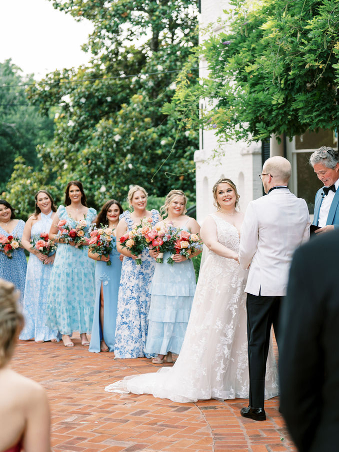 Wedding ceremony with bridesmaids lined up outdoors.