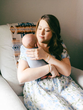 Film newborn photographer in Austin documenting mother holding newborn baby at home