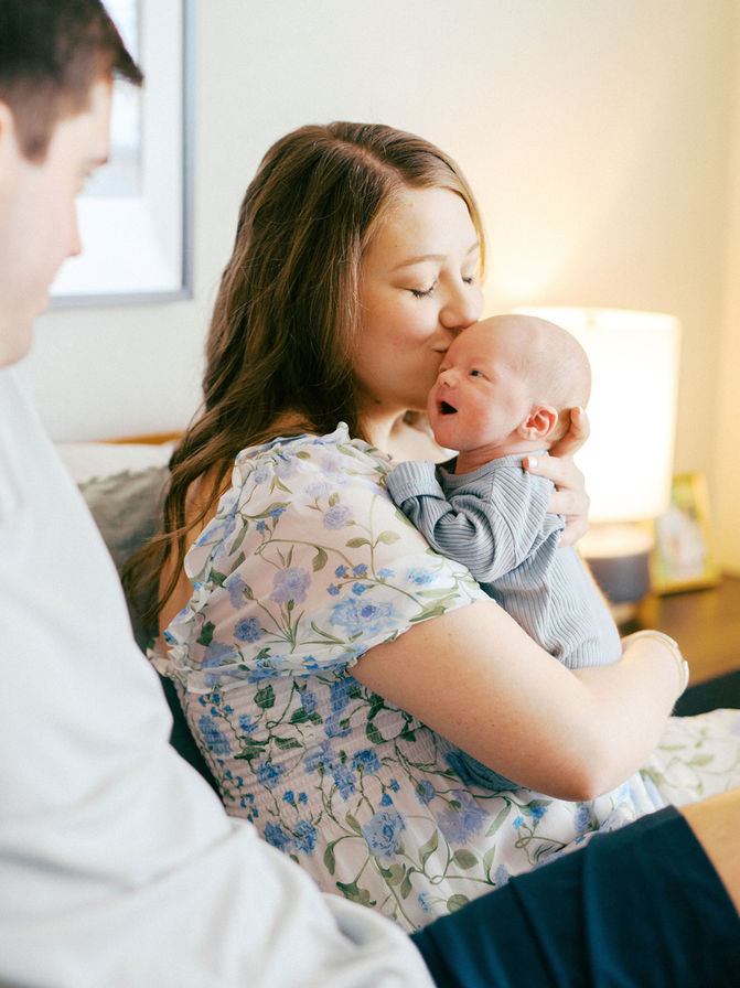 Austin newborn photographer photographing mother cuddling newborn baby in soft natural light