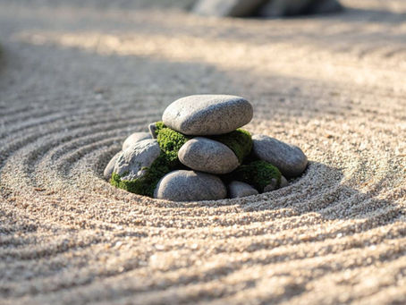Stacked stones with moss in a zen garden setting, surrounded by concentric sand patterns. Peaceful and serene atmosphere. Symbolizing relaxing micro practices during day.