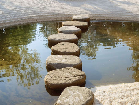 Stone path crosses a tranquil pond in a Zen garden. Sand patterns surround a tree, creating a calm, reflective setting. How resilience strengthens through disengagement and recovery.