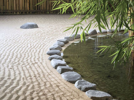 Zen garden with raked sand patterns, large stones lining a pond, and bamboo in the background. Calm and serene atmosphere. Symbolizing healthy boundaries.