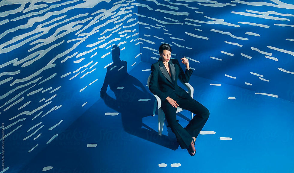 Image of a woman sitting on a white chair in a room with blue and white patterned walls.