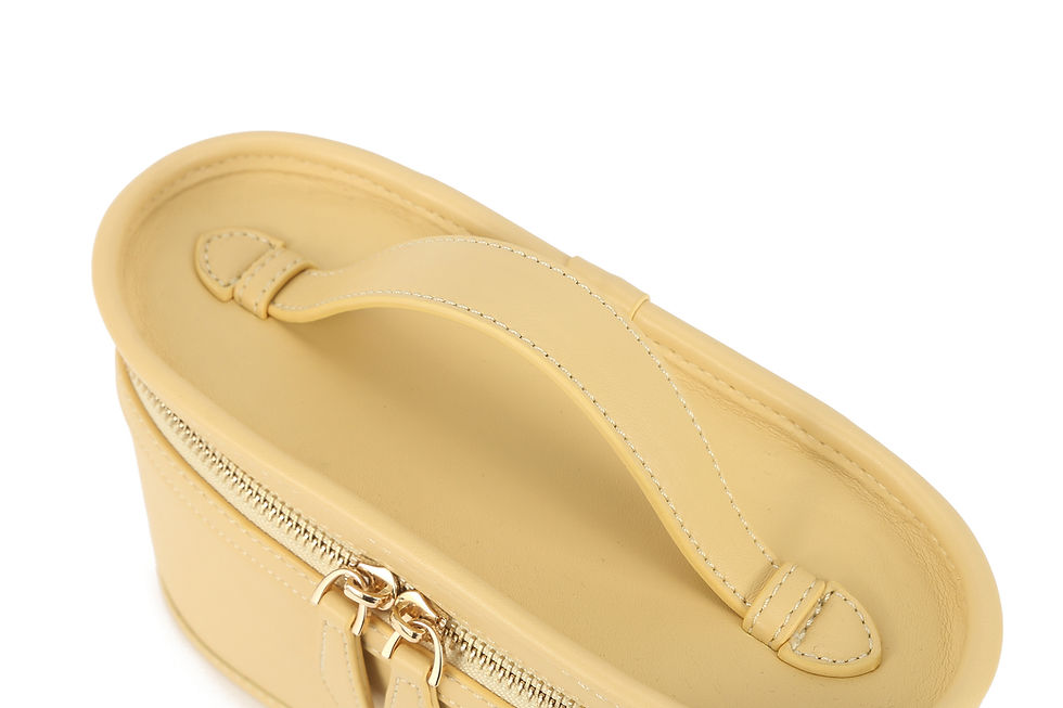 Thumbnail: Pale yellow structured vanity bag with top handle, double zipper pullers, detachable strap, and gold-tone hardware.
