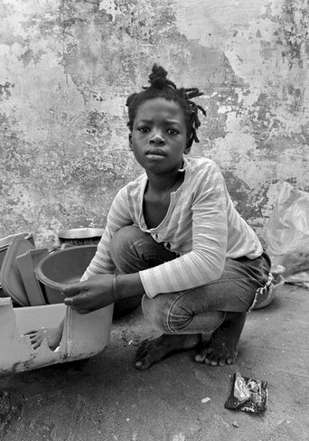 A young girl sitting by the bucket she has been washing clothes in.