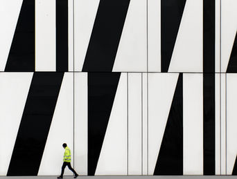 A man (a worker) walks past a distinctly modern building facade near Copenhagen North.