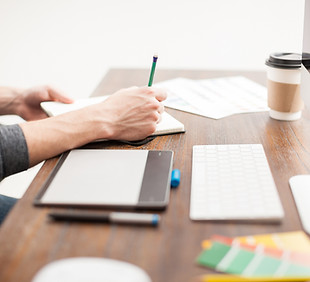 Persoon schrijft in notitieblok op houten tafel bij Myfoodworks