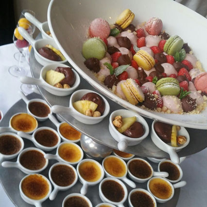 Dessertbuffet met kleurrijke macarons en mini crèmes brûlées.