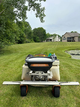Spreader applying fertilizer to lush green lawn