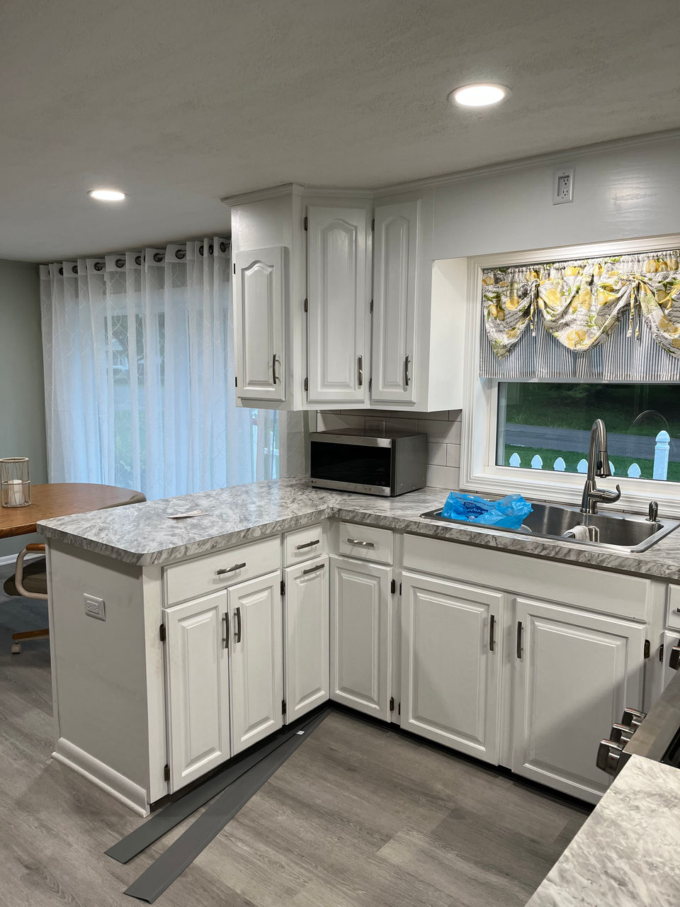 This kitchen is undergoing a dramatic makeover. Bold orange wood cabinets are being replaced with a fresh, clean look of all-white cabinetry. This transformation promises to create a bright and airy space.