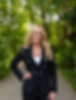 Smiling woman in black blazer, outdoors