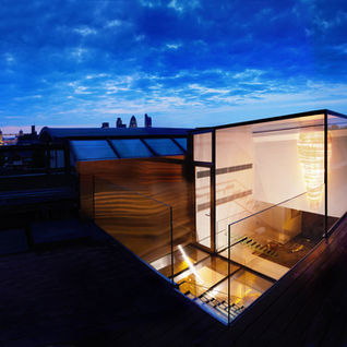 Contemporary home extension featuring structural glass box room illuminated at night