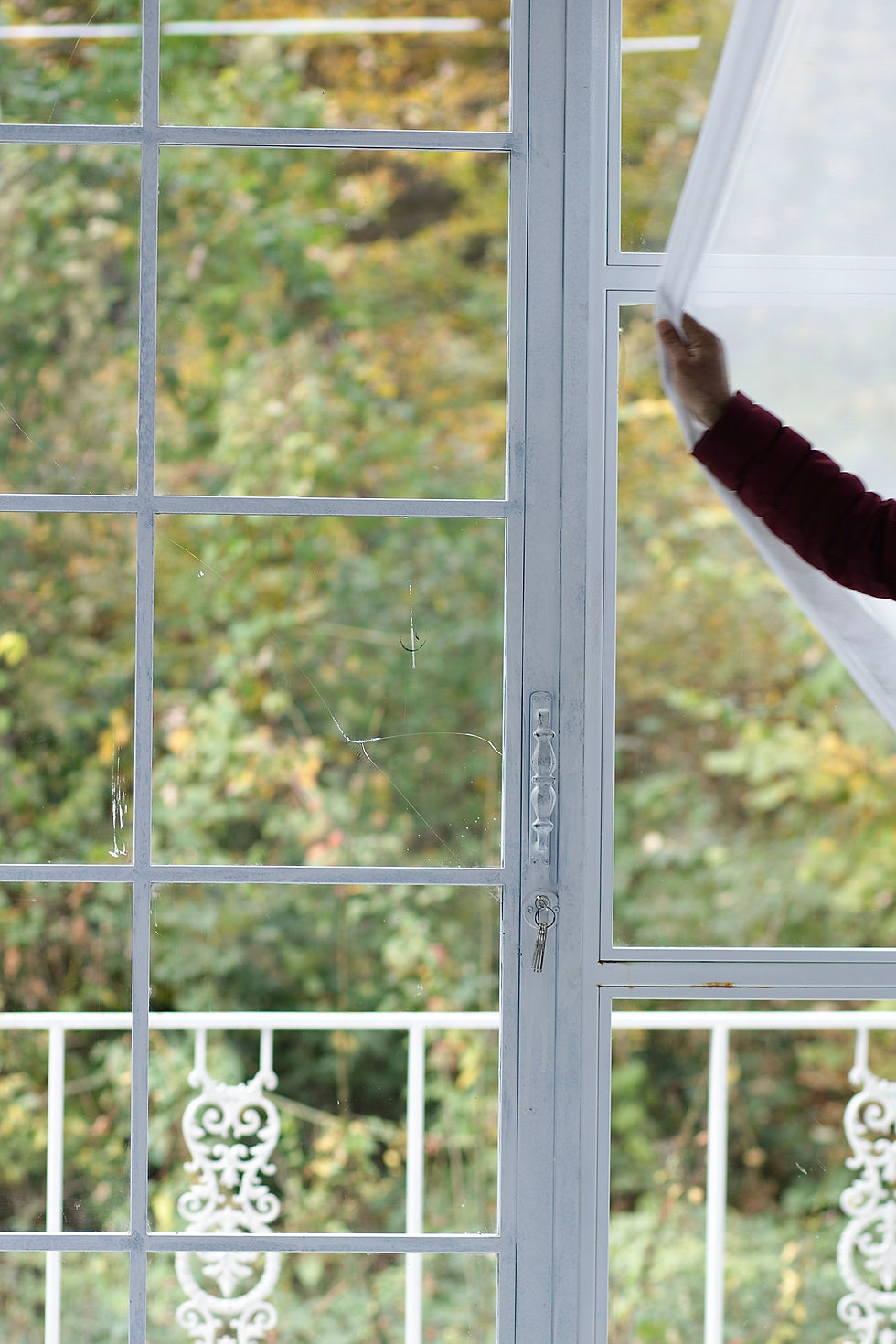person covering window with curtain