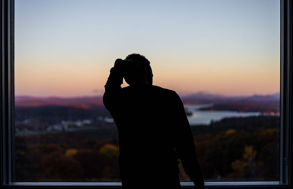 person standing at window with their hand on their head