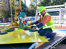 Workers rigging coloured metal panels ready for installation at University of Canterbury.