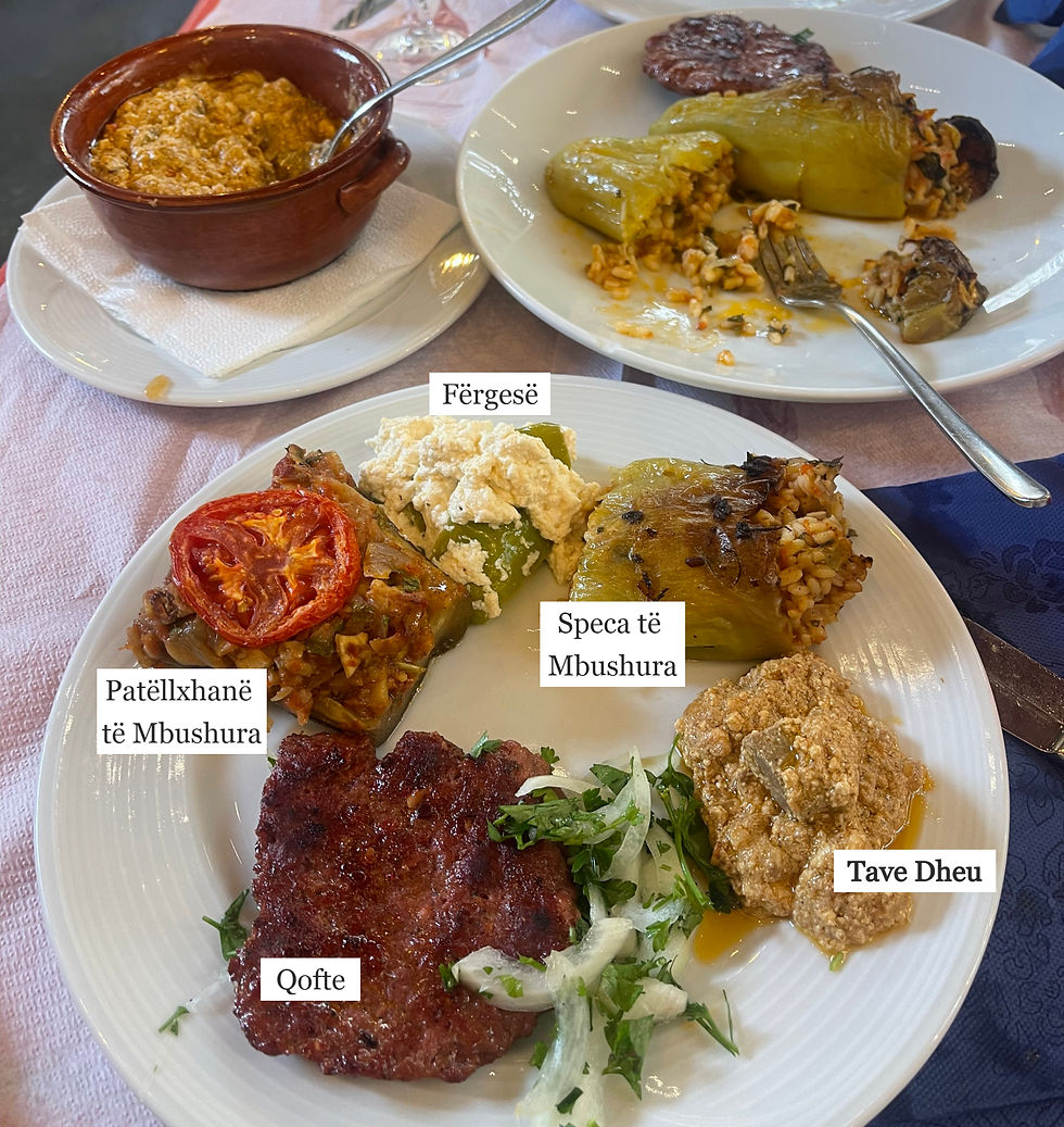 Plates with stuffed bell peppers, minced meat, tomato slice, cheese, and dip. Served on white dishware over a pink tablecloth.