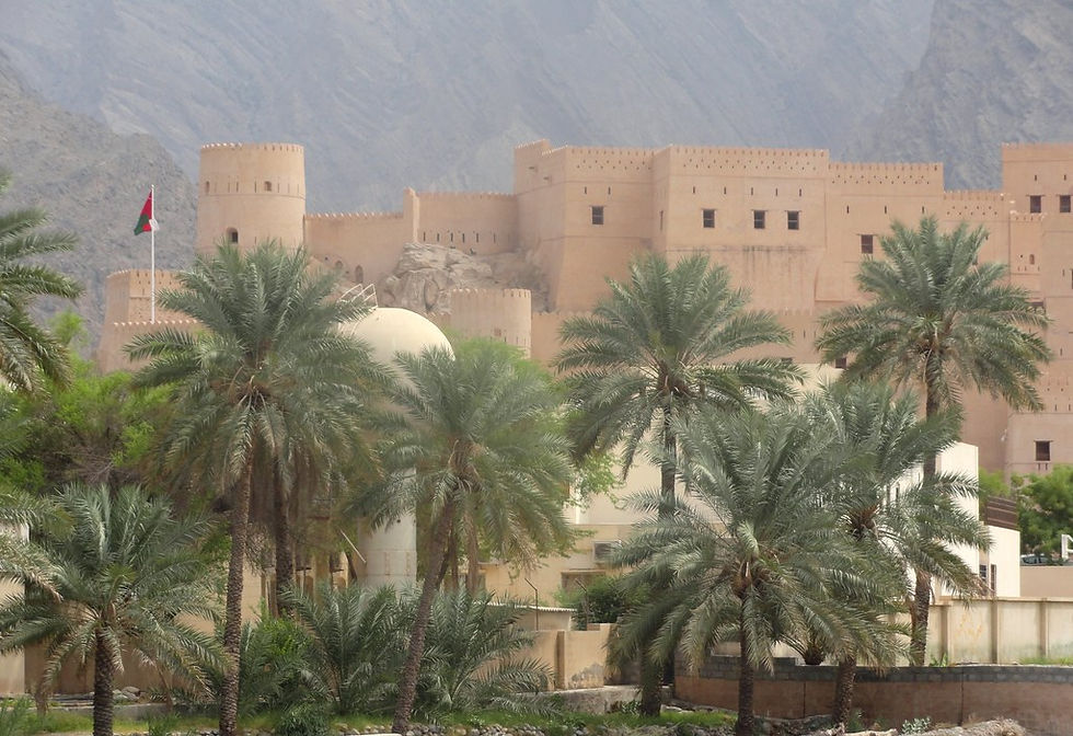 Desert fortress with sandy towers and Omani flag. Palm trees and rugged mountains in the background, creating a historic and serene mood.