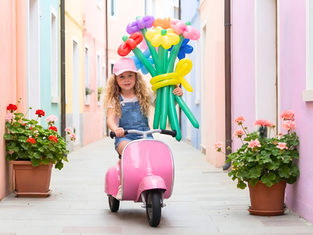 Enfant souriant sur un porteur scooter vintage en métal Primo de la marque Ambosstoys.
