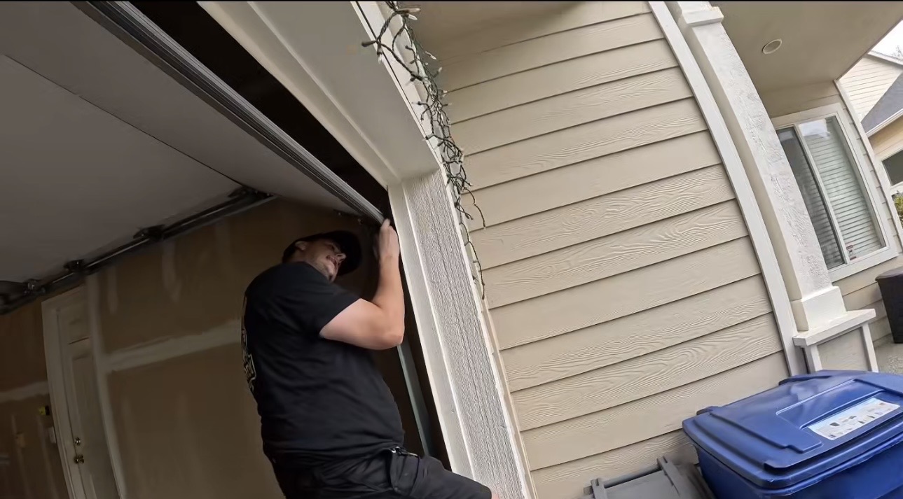 Wesley Zietz working beside the garage door frame at a residential home.